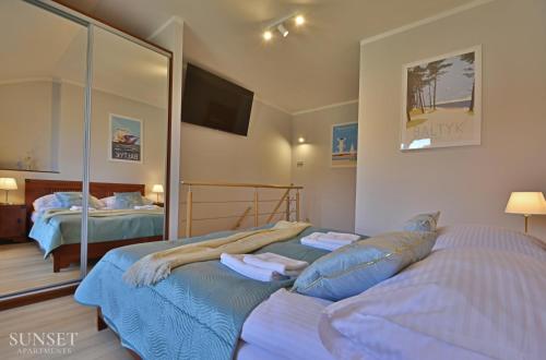 Un dormitorio con dos camas y un espejo. en Sunset Apartments - Uzdrowiskowa - 200m od plaży!, en Świnoujście