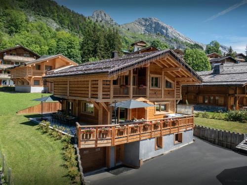 une maison en rondins sur un lac avec des montagnes en arrière-plan dans l'établissement Chalet Trusquin - OVO Network, au Grand-Bornand