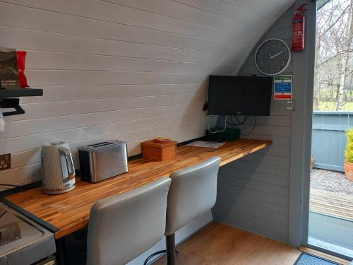 a room with a counter with a television and a desk at Nevis Pod, West Highland Way Holidays in Kinlochleven