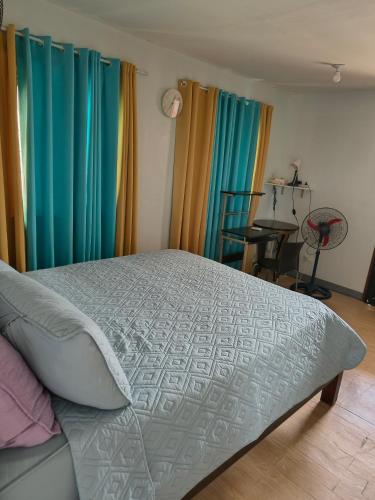 a bedroom with a bed with blue and green curtains at Asuncion Staycation and House rental in San Pablo