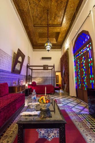 a living room with a table and a stained glass window at Riad - Dar Al Andalous in Fès