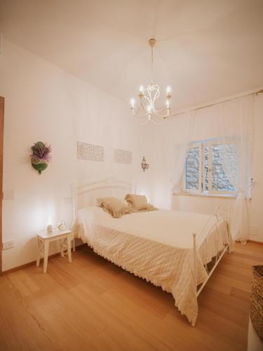 a white bedroom with a bed and a chandelier at dimora 13 in Casale Marittimo