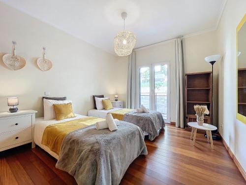 two beds in a white room with wooden floors at Quintas Village AY by Atlantic Holiday in Caniço