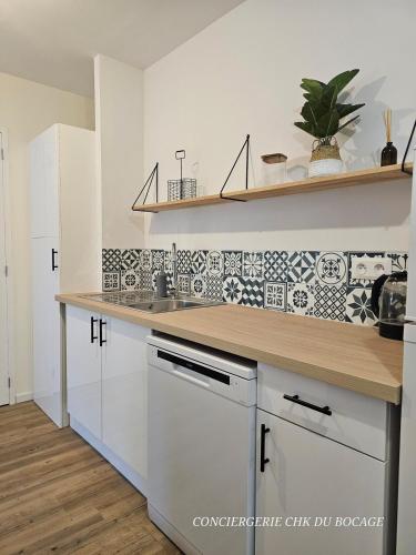 une cuisine avec des armoires blanches et un comptoir dans l'établissement Le Relais 19 centre bourg T4 100m2 - 4min à Puy duFou, aux Épesses