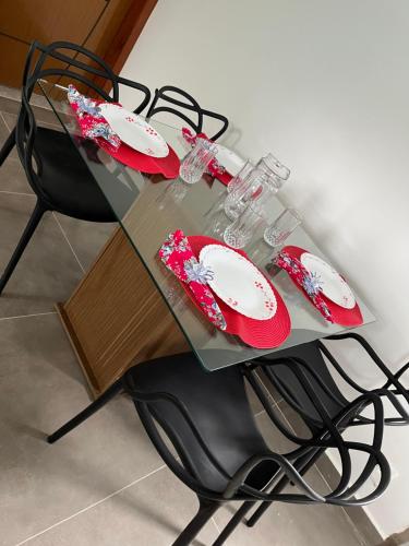 a glass table with red and white plates on it at Casa de praia aconchegante com ar in Serra