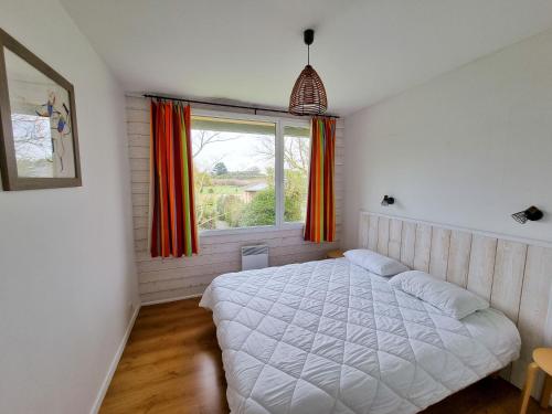 a bedroom with a white bed and a window at Résidence de Nodeven in Guissény