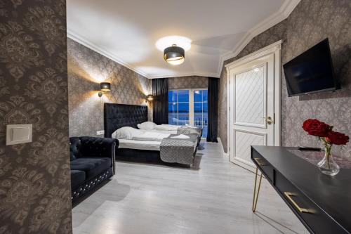 a bedroom with a bed and a couch and a television at Dworek Kurowski in Szczecin