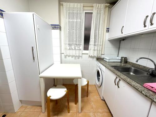 a small white kitchen with a sink and a washing machine at Piso en el corazón de Baiona con vistas al mar in Baiona