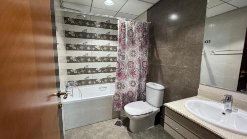 a bathroom with a toilet and a sink and a shower curtain at SeaView Beachfront with pool,sauna,jacuzzi,gym,cafe in Ajman 