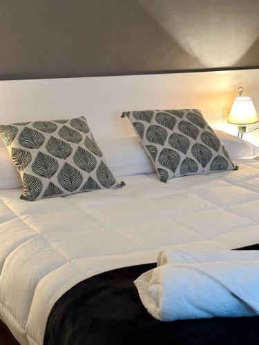 a white bed with two pillows on top of it at Piso en el corazón de Baiona con vistas al mar in Baiona