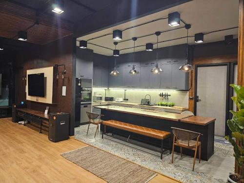 a kitchen with a sink and a counter with chairs at Black Sheep House Khaoyai by ALPHATEL PARTNER in Pong Talong