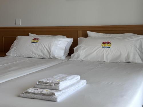 a white bed with two pillows and a pile of towels at BayView Albufeira in Albufeira