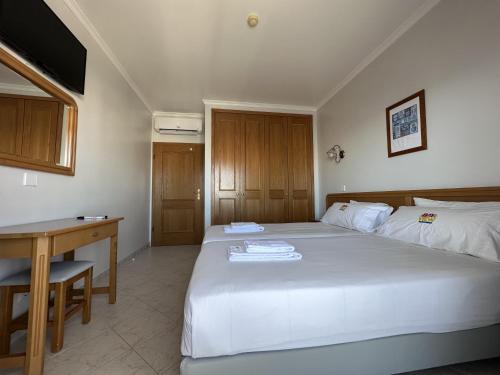a bedroom with a large white bed and a desk at BayView Albufeira in Albufeira