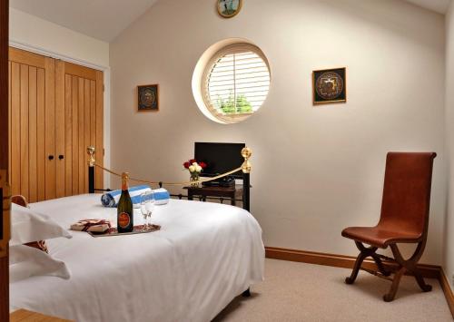 a bedroom with a bed and a chair and a window at Finest Retreats - The Loft in Kingham