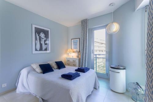 une chambre avec un lit aux murs bleus et une fenêtre dans l'établissement Le Goya by Halldis, à Cannes