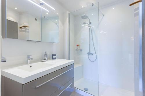 une salle de bain blanche avec un lavabo et une douche dans l'établissement Le Goya by Halldis, à Cannes