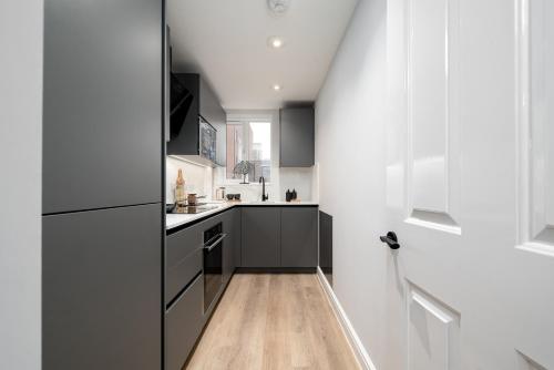a kitchen with black and white cabinets and a wooden floor at 62 Park Street - Urban Apartments in Bristol