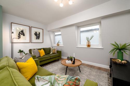 a living room with a green couch and yellow pillows at 62 Park Street - Urban Apartments in Bristol