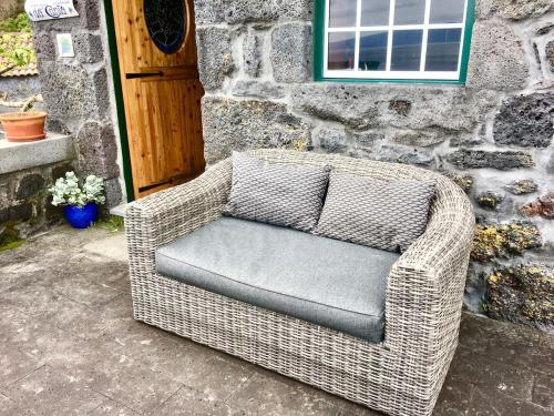 a wicker chair sitting in front of a building at Adega Baia do Canto AL 1398 in Terra Alta