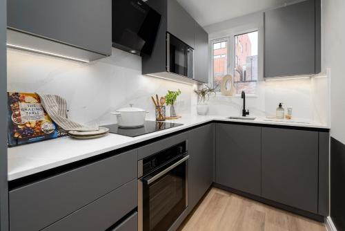 a kitchen with black cabinets and white counter tops at 62 Park Street - Urban Apartments in Bristol