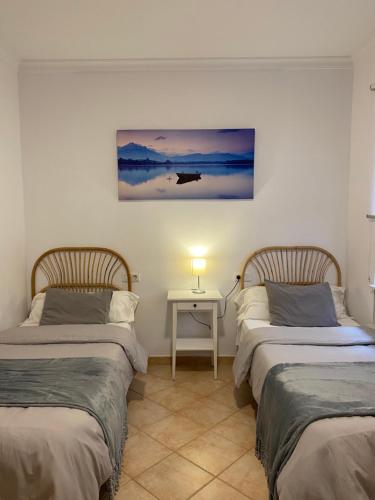 two beds in a room with a table and a painting at Vivienda 2 dormitorios Churriana-Aeropuerto in Málaga