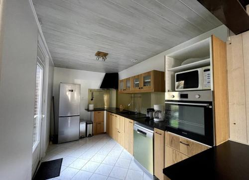 une cuisine avec des armoires en bois et des appareils en acier inoxydable dans l'établissement Au gîte du Roy, à Roye