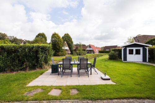 a patio with chairs and a table in a yard at Bladkoning I Trendy Huisje met Openhaard in Zwiggelte