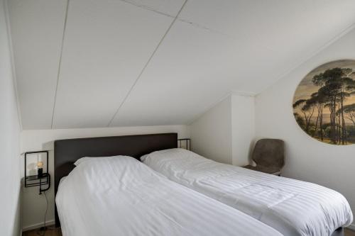 a bedroom with two white beds and a chair at Bladkoning I Trendy Huisje met Openhaard in Zwiggelte