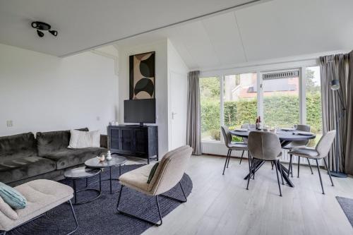 a living room with a couch and a table and chairs at Bladkoning I Trendy Huisje met Openhaard in Zwiggelte