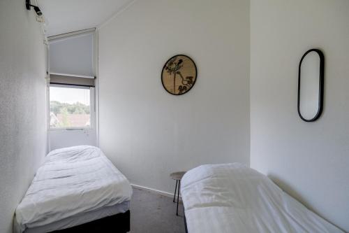 a room with two beds and a clock on the wall at Bladkoning I Trendy Huisje met Openhaard in Zwiggelte