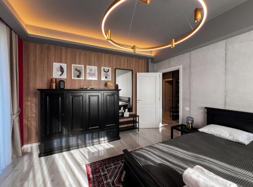 a bedroom with a black bed and a chandelier at GreenTeam Apartments in Râmnicu Vâlcea