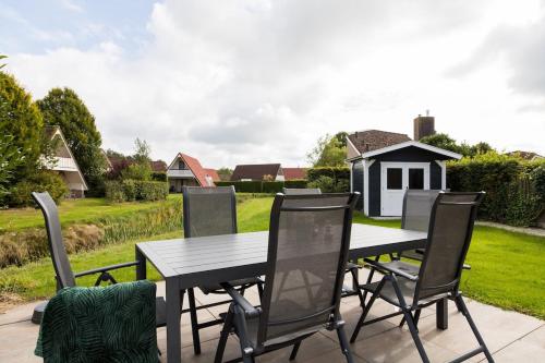 a table and chairs on a patio with a yard at Bladkoning I Trendy Huisje met Openhaard in Zwiggelte
