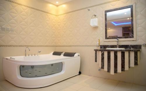 a bathroom with a tub and a sink and a mirror at توارن للشقق المخدومة الاقتصادية in Riyadh