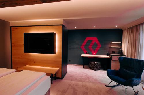 a hotel room with a bed and a tv and a desk at Hotel Alpenkönig in Oberstaufen