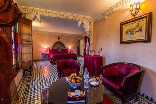 a room with two beds and a table and chairs at Riad - Dar Al Andalous in Fès