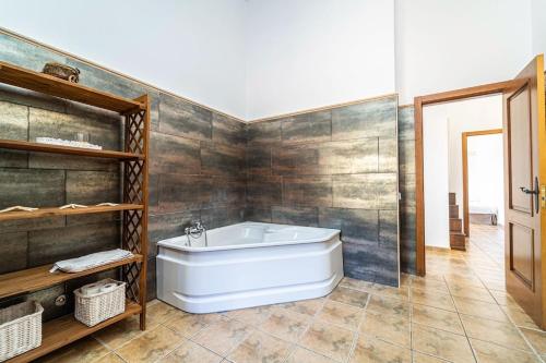 a bathroom with a white tub and wooden walls at Villa Sunset Boulevard Lujo in Puntiró