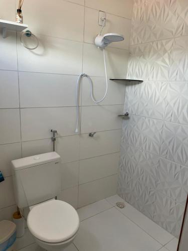 a white bathroom with a toilet and a shower at Brisa Bitingui in Japaratinga