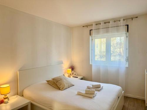 une chambre blanche avec un lit avec des serviettes dessus dans l'établissement Au grand 6 de Reims Cathédrale, à Reims