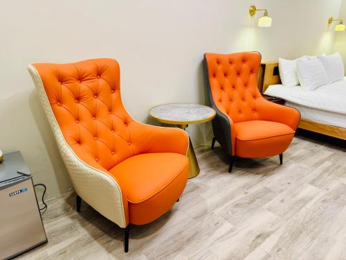 two orange chairs and a bed in a room at 芊禹民宿 - 走路就到鐵花村-微光集-觀光夜市 - in Taitung City