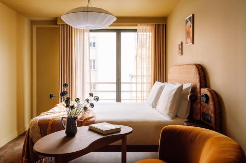 a hotel room with a bed and a table and a window at Le Jardin de Verre by Locke in Paris