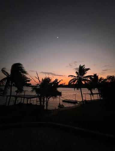 a sunset on a beach with palm trees and the ocean at Hotel Fazenda Monte Cristo in Piranhas