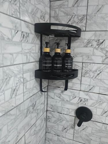 a group of four bottles on a wall in a bathroom at The Hideaway Cabin in Pretoria