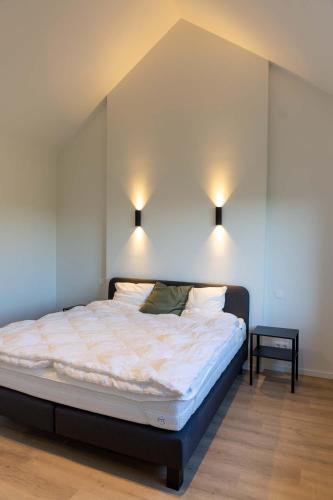 a bed in a room with two lights on the wall at Villa Armande in Zammelen