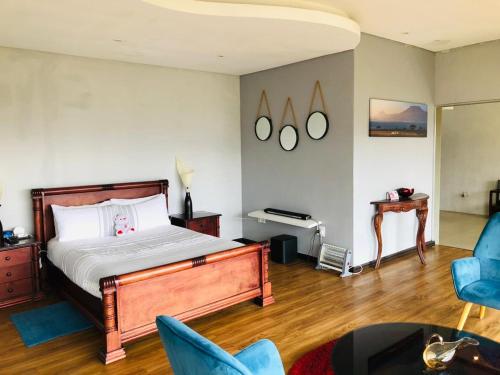 a bedroom with a bed and a piano and blue chairs at At TheSoil in Edendale