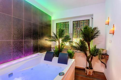 ein Badezimmer mit einer Badewanne mit zwei Stühlen und Pflanzen in der Unterkunft Vintage Suite mit Jacuzzi und Sauna in Essen