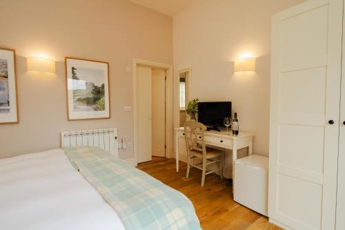 a bedroom with a bed and a desk with a computer at Crepe Farm Barns in Bridport