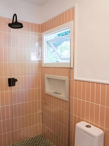 a bathroom with a toilet and a window at Vila Corada in Pipa