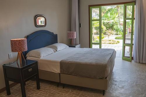 a bedroom with a bed and a door to a patio at Vila Corada in Pipa