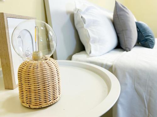 a wicker table with a glass lamp on it next to a bed at QuickHome - Appartamento Mazzini in Biella