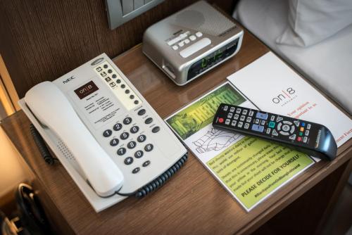 a telephone and a remote control on a desk at On 8 Sukhumvit Nana Bangkok by Compass Hospitality in Bangkok